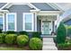 Inviting covered front porch with a stylish turquoise door and lush landscaping at 209 Stone River Dr, Wendell, NC 27591