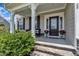 Inviting covered porch with stone steps, seating, and black front door at 243 E Wellesley Dr, Clayton, NC 27520