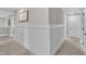 Well-lit hallway featuring wainscoting and neutral carpeting leading to various rooms at 243 E Wellesley Dr, Clayton, NC 27520