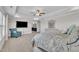 Bright main bedroom featuring a tray ceiling, TV and a view into the ensuite bathroom at 243 E Wellesley Dr, Clayton, NC 27520
