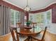 Elegant dining room with a round wood table, chandelier, and multiple windows offering scenic views at 244 Elmcrest Dr, Holly Springs, NC 27540