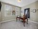 Bright, carpeted home office featuring a wood desk, neutral walls, and natural light through two windows at 244 Elmcrest Dr, Holly Springs, NC 27540