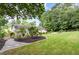 Landscaped backyard with mature trees, stone path, and grassy area, perfect for outdoor activities at 281 Kinsman Ct, Fuquay Varina, NC 27526