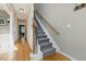 Bright hallway with hardwood floors and a staircase with carpet steps and iron handrail at 2933 Creek Moss Ave, Wake Forest, NC 27587