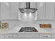 Close-up of a modern stovetop with stainless steel vent hood and white tile backsplash at 2969 Thirlestane Dr, Apex, NC 27502