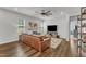 Spacious living room featuring hardwood floors, a leather sofa, and ample natural light from the windows at 2969 Thirlestane Dr, Apex, NC 27502