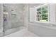 Bathroom with glass-enclosed shower, white marble tile, and white shutters at 305 Lochridge Dr, Roxboro, NC 27573