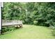 Spacious backyard featuring a wooden deck, lush green grass, mature trees, and plenty of room to roam at 3110 Trinness Dr, Durham, NC 27707