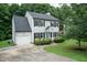Traditional two-story house with a garage, manicured lawn, blue door, and mature trees creating a serene landscape at 3110 Trinness Dr, Durham, NC 27707