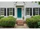 Welcoming front entrance with a blue door, brick steps, manicured bushes, and decorative wall lanterns at 3110 Trinness Dr, Durham, NC 27707