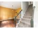 Carpeted staircase with painted wood trim near a sunny living room featuring hardwood floors and warm yellow walls at 3110 Trinness Dr, Durham, NC 27707