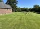 Backyard view features well-maintained lawn, play set, mature trees, and lake in the distance at 3537 Sweetgum Rd, Gibsonville, NC 27249