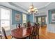 A dining room is shown with a chandelier above a wooden table with six chairs with blue walls and three windows at 3720 Bridgeton Park Dr, Raleigh, NC 27612
