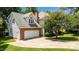 View of the home's garage and extended driveway surrounded by lush landscaping at 3720 Bridgeton Park Dr, Raleigh, NC 27612