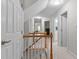 Upstairs hallway featuring natural wood banisters, lighting and doorways leading to different rooms at 3720 Bridgeton Park Dr, Raleigh, NC 27612