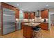 A kitchen is shown with an island and two stools with stainless steel appliances and wooden cabinets at 3720 Bridgeton Park Dr, Raleigh, NC 27612