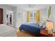 Bright bedroom features blue bedding, hardwood floors, and windows with yellow curtains at 414 W Markham Ave, Durham, NC 27701