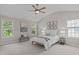 Bright bedroom featuring a ceiling fan, neutral walls, white bedding, and natural light from large windows at 4804 Carmen Ln, Durham, NC 27707