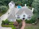 Expansive aerial view of a white brick home with a backyard pool and a detached garage among lush trees at 5005 Lenoraway Dr, Raleigh, NC 27613