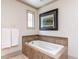 Bathroom with neutral tiling around a built in tub, decorative tile detail, and decorative window at 5005 Lenoraway Dr, Raleigh, NC 27613
