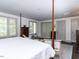 Four poster bed with neutral quilt in a room with neutral walls, dark floors, and decorative window at 5005 Lenoraway Dr, Raleigh, NC 27613