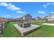 Green backyard with a lounge seating area on a wooden deck, and a fire pit area at 525 Willow Breeze Ct, Zebulon, NC 27597