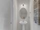 Well-lit half bathroom with a pedestal sink, an oval mirror, and decorative wall art, offers a modern and clean space at 525 Willow Breeze Ct, Zebulon, NC 27597