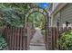 Charming garden entrance with arched wooden gate, inviting gravel pathway, and lush greenery at 5309 Overtop Ln, Raleigh, NC 27613