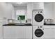 Well-lit laundry room boasts modern appliances, ample counter space, and sleek white cabinets at 5309 Overtop Ln, Raleigh, NC 27613