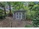Backyard featuring a charming storage shed with a pathway, surrounded by mature trees and shrubs at 5309 Overtop Ln, Raleigh, NC 27613