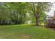 Lush backyard with large shade tree, wooden steps leading to a small deck, and a storage shed at 601 E Franklin St, Raleigh, NC 27604