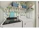 Well-lit laundry room featuring a cactus-themed wallpaper, front loading washer and dryer, and storage shelves at 601 Texanna Way, Holly Springs, NC 27540