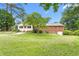 Expansive backyard with lush green lawn, mature trees, and a brick house with a back patio, perfect for outdoor living at 619 S Fifth St, Mebane, NC 27302