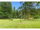 Picturesque backyard featuring a well-manicured lawn, mature trees, and a vintage clothesline adding to the scenic view at 619 S Fifth St, Mebane, NC 27302