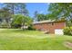 Spacious backyard with lush green lawn, mature trees, and a well-maintained brick home, perfect for outdoor activities at 619 S Fifth St, Mebane, NC 27302