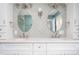 Up close, this bathroom vanity features tiled backsplash, a double sink, modern lighting, and matching oval mirrors at 619 S Fifth St, Mebane, NC 27302