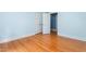 Bright bedroom featuring hardwood floors, blue walls and white trim, with an open door leading to another room at 619 S Fifth St, Mebane, NC 27302