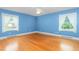 Bright bedroom with hardwood floors, a ceiling fan, and two windows offering ample natural light and views at 619 S Fifth St, Mebane, NC 27302