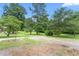 Well-maintained front yard featuring a gravel driveway, mature trees, and lush greenery, creating a serene setting at 619 S Fifth St, Mebane, NC 27302
