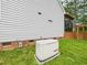 View of the home's exterior with a generator in the backyard on a green lawn at 7501 Montibillo Pkwy, Durham, NC 27713