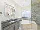 Bathroom with granite countertops, soaking tub, glass shower, and mosaic tile at 7501 Montibillo Pkwy, Durham, NC 27713
