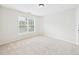 Bright bedroom featuring neutral carpet, light-colored walls, and natural light from a large window at 7501 Montibillo Pkwy, Durham, NC 27713