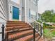 Inviting entrance with brick steps, white railings, and a charming blue front door at 7501 Montibillo Pkwy, Durham, NC 27713