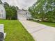 Home featuring a long driveway leading to a two-car garage, green lawn, and mature trees at 7501 Montibillo Pkwy, Durham, NC 27713
