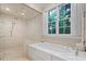 Luxurious bathroom featuring a standalone tub, tiled shower, and large window at 800 Lakestone Dr, Raleigh, NC 27609