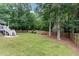 A sprawling green backyard with a white deck, a wooden fence, and mature trees at 1001 Kingsway Dr, Apex, NC 27502