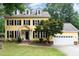 Charming yellow two-story home with black shutters and manicured lawn and white garage door at 1001 Kingsway Dr, Apex, NC 27502