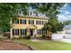 Charming yellow two-story home with black shutters, dormers, and manicured lawn at 1001 Kingsway Dr, Apex, NC 27502
