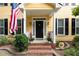Inviting front porch with black door, American flag, sconces, and brick steps at 1001 Kingsway Dr, Apex, NC 27502