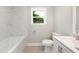 A newly renovated bathroom with a tub and shower combination, neutral tones and a window at 1006 S Second Ave Ave, Siler City, NC 27344